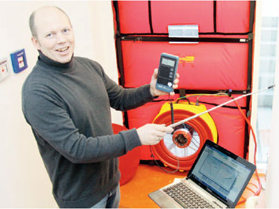 Ian Jack untersucht die Luftströmung. Hinter ihm ist das kalibierte Gebläse zu erkennen, mit dem Unter- und Überdruck im Stadtwerke Neubau erzeugt wird. Ian Jack untersucht die Luftströmung. Hinter ihm ist das kalibierte Gebläse zu erkennen, mit dem Unter- und Überdruck im Stadtwerke Neubau erzeugt wird.